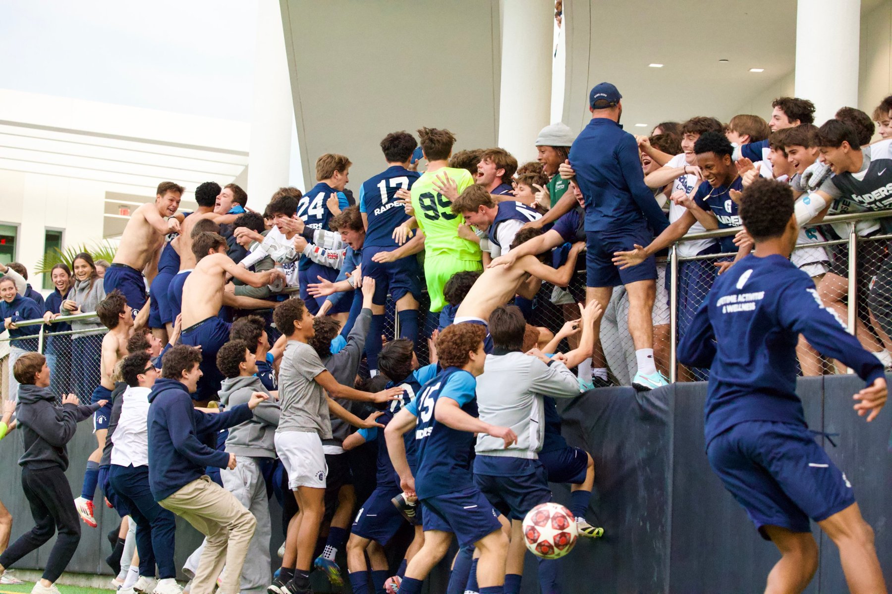 Raiders players climbing into the student section to celebrate as a ball flies past