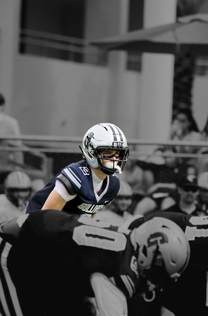 Gulliver football player in navy reading the defense, in color against a black-and-white crowd